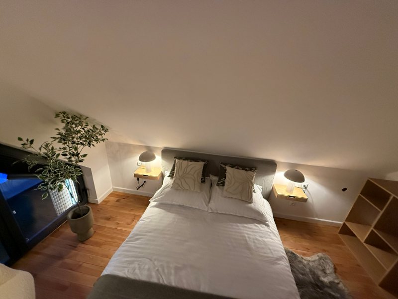Sypialnia z łóżkiem małżeńskim i lampkami nocnymi pod skosem dachu