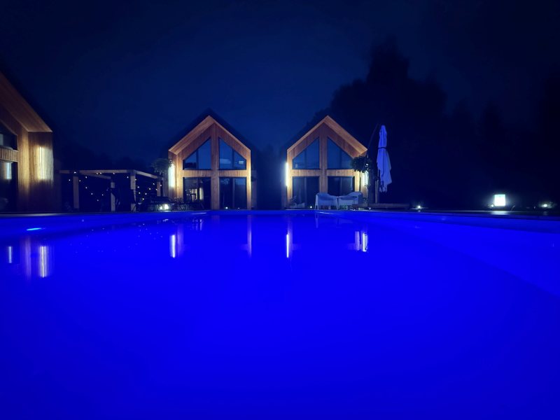 Lustro wody basenu i odbicia świateł domków nocą